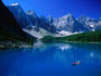 People paddling their canoe on the impossibly blue waters of Moraine Lake, surrounded by the Rocky Mountains in the Banff National Park.