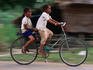 Girls riding bicycle in Bavel village.
