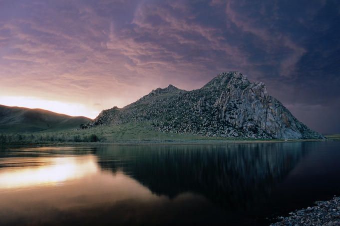 Mountain by a lake at sunset.