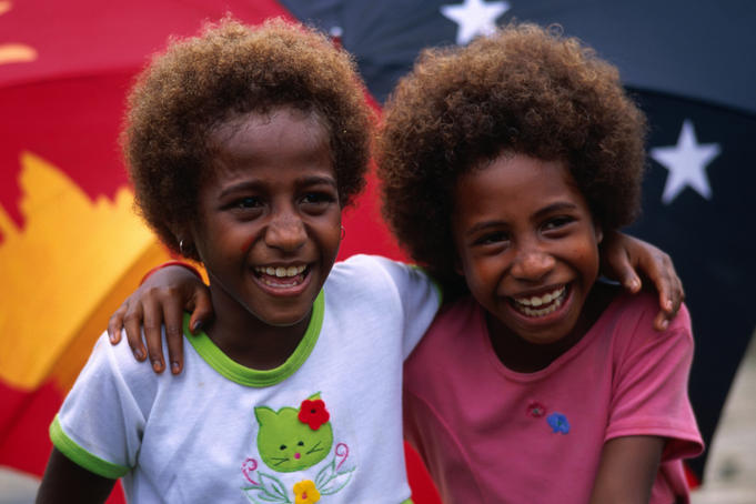 Two young girls from Madang in front of the PNG flag.