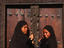 Young Islamic girls in traditional bui-bui stand in front of a typical Zanzibar doorway in Lamu.