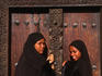 Young Islamic girls in traditional bui-bui stand in front of a typical Zanzibar doorway in Lamu.