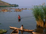People in dugout canoes fishing on the lake.