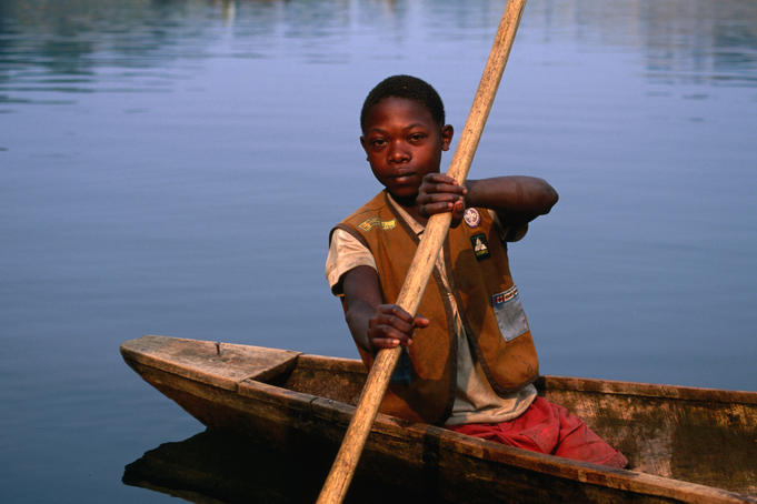 A boy rows a dugout canoe out to fish on the lake.