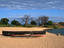 Moored fishing boat and baobab trees on Kaya Mawa Beach, Lake Malawi.