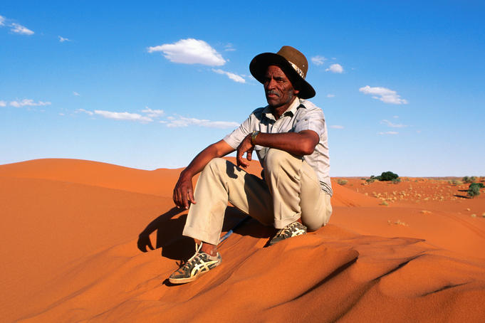 Sheep farmer sitting on dune.