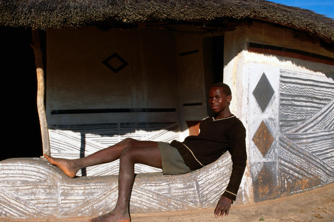 Man outside decorated Ndebele house.