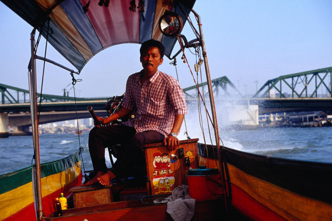 Driver on long tail boat on the Chao Phraya (River).
