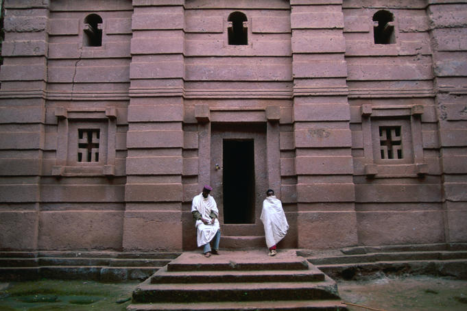 Two robed men on the steps of the patterned church of Beta Giorgis, hewn from rock