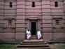 Two robed men on the steps of the patterned church of Beta Giorgis, hewn from rock