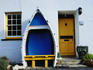 White-washed cottage with outdoor seat in old boat.
