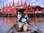 Man in pirogue in front of hotel on stilts.
