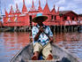 Man in pirogue in front of hotel on stilts.