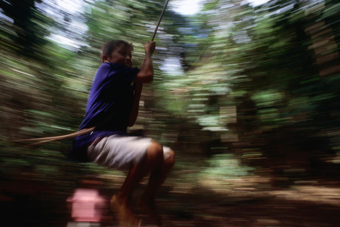 Boy rope swinging off tree.