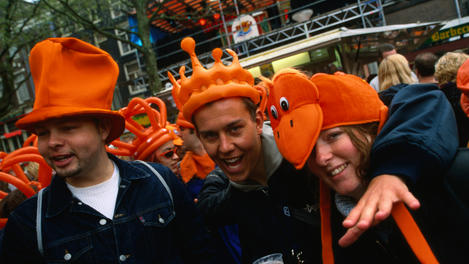 Partygoers wearing orange novelty hats celebrate  Queen's Day on Thorbeckeplein.