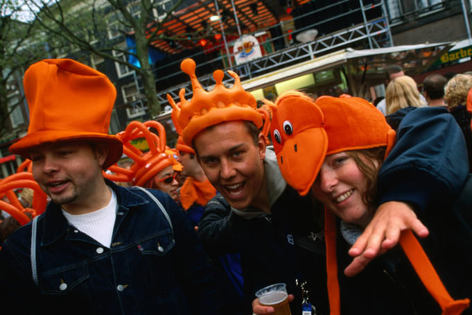 Partygoers wearing orange novelty hats celebrate Queen's Day on Thorbeckeplein.