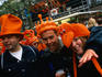 Partygoers wearing orange novelty hats celebrate Queen's Day on Thorbeckeplein.