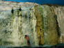 A man standing under a cascade of mineral rich water.