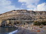 People sun-bathing on the sheltered beach at Matala. The beach is edged by cliffs sporting man-made caves that date back to prehistoric times.