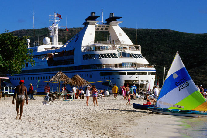 Tourists on beach with cruise ship in background.