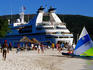 Tourists on beach with cruise ship in background.