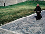 A priest walks past a grassy lawn in Assisi.