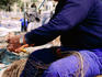 Fisherman mending net at harbour.