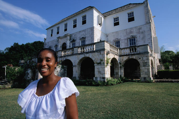 A smiling woman stands outside Rose Hall Great House.