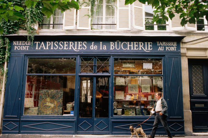 Man walking dog outside Tapisseries de la Boucherie needlework shop.