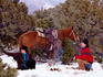 Cowboy, cowgirl and horse around fire in snow.