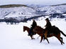 Cowboys galloping through snow.