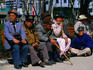Elderly men, all wearing hats, sitting on, and beside park benches in Tapgol Park.