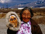 Old woman holding up an Eskimo mask.