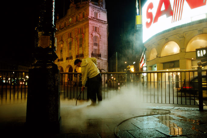 Street cleaner at Piccadily Circus at night.