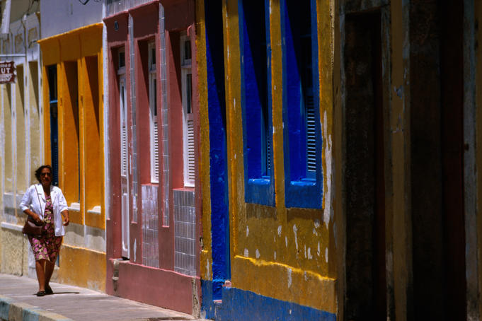 Woman walking along street with colonial facades, Olinda