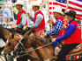 Cowboys holding an American flag on horseback in rodeo arena during rodeo competition at Mashantucket Pequot Tribal Nation hosted Schemitzun Powwow.