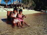A pair of girls sitting on a chair in the shallow waters.