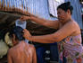A mother gives her young daughter a bath in the morning light behind their shack on Ao Ton Sai beach.