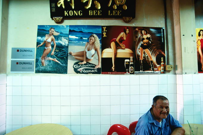 Man sitting in front of beer posters in cafe.