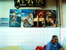 Man sitting in front of beer posters in cafe.