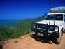 An off-road vehicle on the side of the road with view from Cooktown Hill.