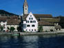 Row boat on the Rhine river in Stein am Rhein with the former Benedictine monastery of St Georgen and 12th century Stadkirche.