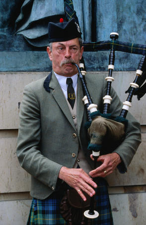 Piper playing bagpipes in Royal Mile.