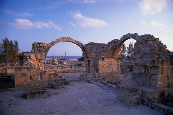 Saranda Kolones ruins at dusk in Kato Phaphos with the harbour in the background.