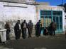 Men leaning against wall talking.