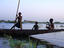Three boys play on a canoe (pirogue) on the river in Mopti.
