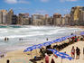 Beachgoers and umbrellas on city beach.