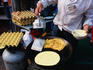 Muslim woman cooking pancakes at stall.