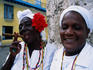 Black women in white clothing pose for tourists.