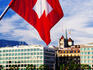 Swiss flag on Mont Blanc Bridge with Quai General Guisan in background.